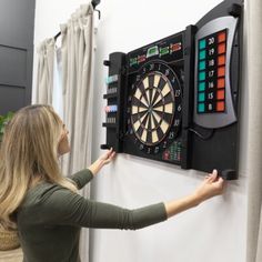 a woman is playing darts on the wall mounted dart board with magnetic numbers and lights