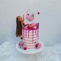 a barbie doll is sitting on top of a pink and white striped cake with a bottle of booze next to it