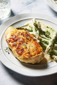 a white plate topped with meat and asparagus