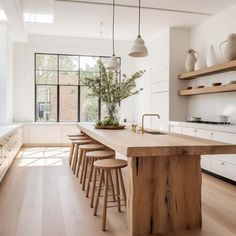 a kitchen with wooden counters and stools next to an island in front of a window