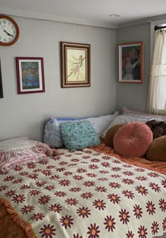 a bed sitting in a bedroom next to a window with pictures hanging on the wall