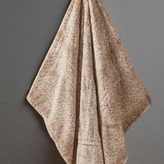 a towel hanging on the wall in front of a gray wall with a wooden hook