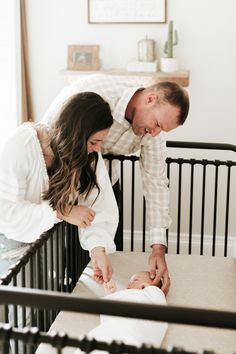 a man and woman standing next to a baby in a crib