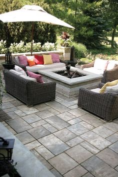 an outdoor living area with couches, tables and umbrellas in the middle of it