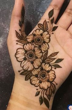 a woman's hand with henna tattoos and flowers on the palm, which is decorated