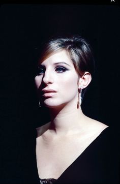 a woman in a black dress is posing for a photo with earrings on her head