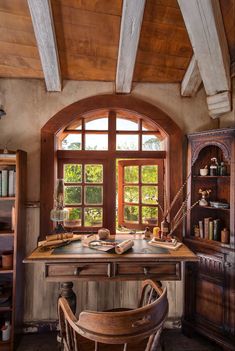 an old fashioned desk and chair in front of a large window