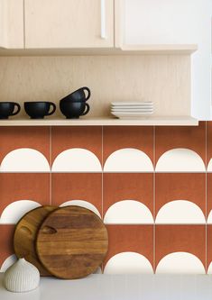 a wooden cutting board sitting on top of a counter next to a vase and bowl