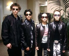 four young people standing next to each other in front of a potted palm tree