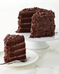 a piece of chocolate cake on a white plate with a fork next to the slice