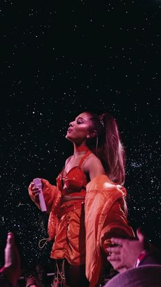 a woman in an orange dress standing on stage