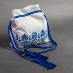 a white bag with blue trim and tassels on the inside is sitting on a gray surface