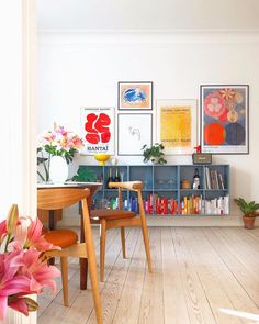 a living room filled with lots of furniture and art on the wall next to a wooden table