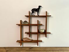 a wooden shelf with two sculptures on top of it and a dog figurine on top