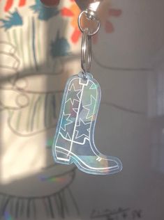 a pair of boots is hanging from a keychain in front of a flowered wall