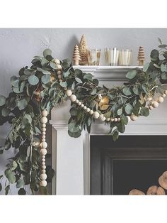 a fireplace mantel decorated with greenery and candles