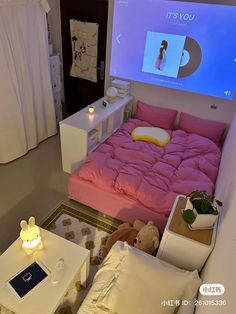 a bed with pink sheets and pillows in a room that has a projector screen on the wall