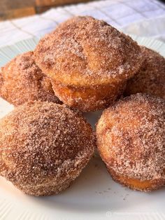 four sugared doughnuts on a white plate