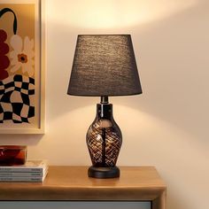 a lamp sitting on top of a wooden table next to a book shelf and painting