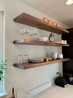 two open shelves in a kitchen with dishes and wine glasses on the top one shelf