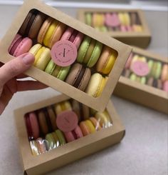 a person is holding up a box of macaroons