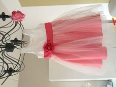 a pink and white dress hanging from a chandelier with flowers on it's side