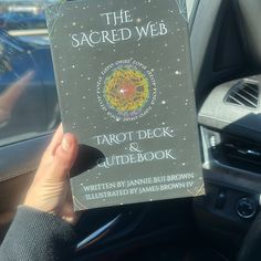 the sacred web tarot deck and guide book is held in someone's hand