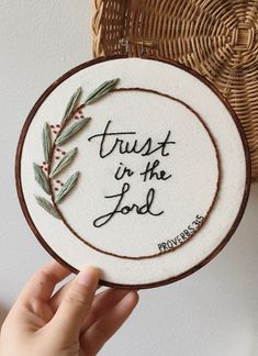 someone is holding up a cross stitch hoop with the words trust in the lord on it