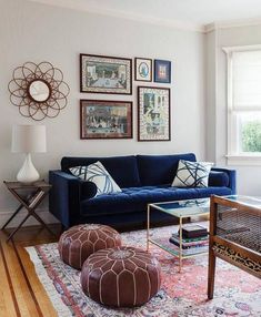 a living room with blue couches and pictures on the wall above them, along with two foot stools