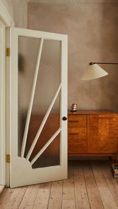 an open door leading to a bedroom with wooden flooring and white walls in the background