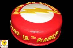 a red cake with white and yellow frosting has the flash symbol on it's side