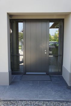 the front entrance to a modern home with two doors and shutters on both sides