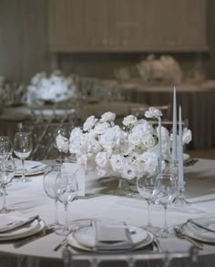 the table is set with white flowers and silverware