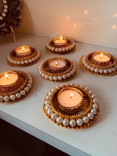 some candles are sitting on a table with pearls and beads around them in the shape of circles