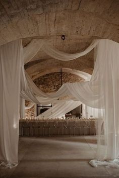 a room that has some white drapes on the ceiling and tables in front of it