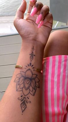 a woman's arm with a flower tattoo on the left side of her wrist