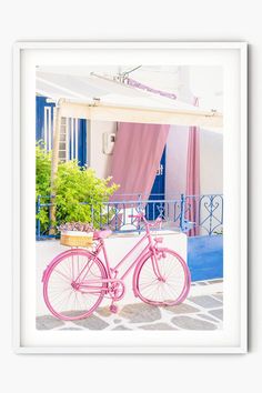 a pink bike parked in front of a blue and white building with curtains on it