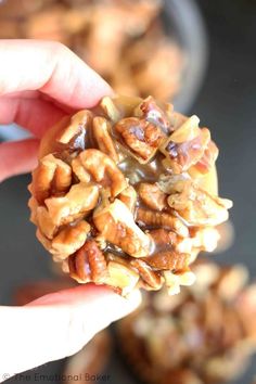 someone holding up a cookie with nuts on it