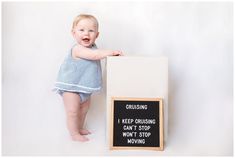 a baby standing next to a sign that says cruising can't stop won't stop moving