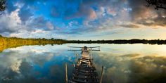 a boat sitting on top of a body of water under a sky filled with clouds