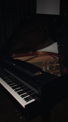 a black piano in the dark with its lights on