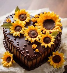 a heart shaped chocolate cake with sunflowers on top, sitting on a napkin