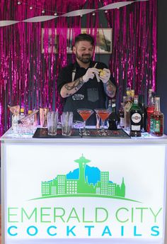 a man standing behind a bar filled with drinks