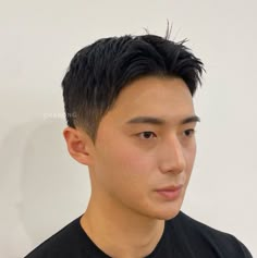 a young man with black hair is looking at the camera while wearing a black t - shirt