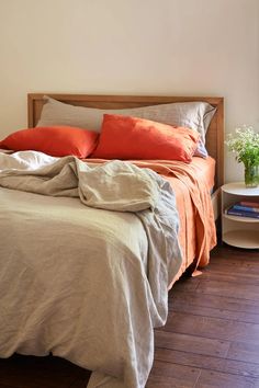 a bed with two pillows and an orange blanket on top of it in a bedroom