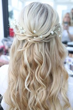 the back of a woman's head with long blonde hair and flowers in her hair