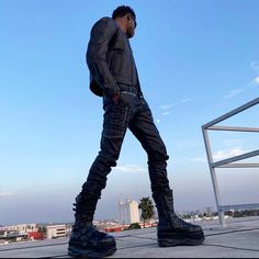 a man standing on top of a roof next to a metal rail with his foot in the air