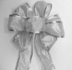 a large silver bow on top of a white wall