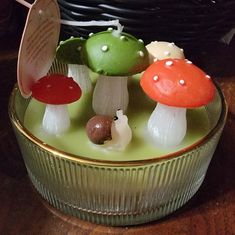 several small mushrooms sitting on top of a glass container with spoons in it and one mushroom sticking out of the middle