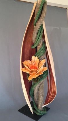 an art piece made out of wood and rope with a flower on the end of it